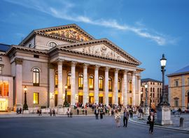 Außenansicht der Bayerischen Staatsoper München mit Besuchern im Vordergrund.